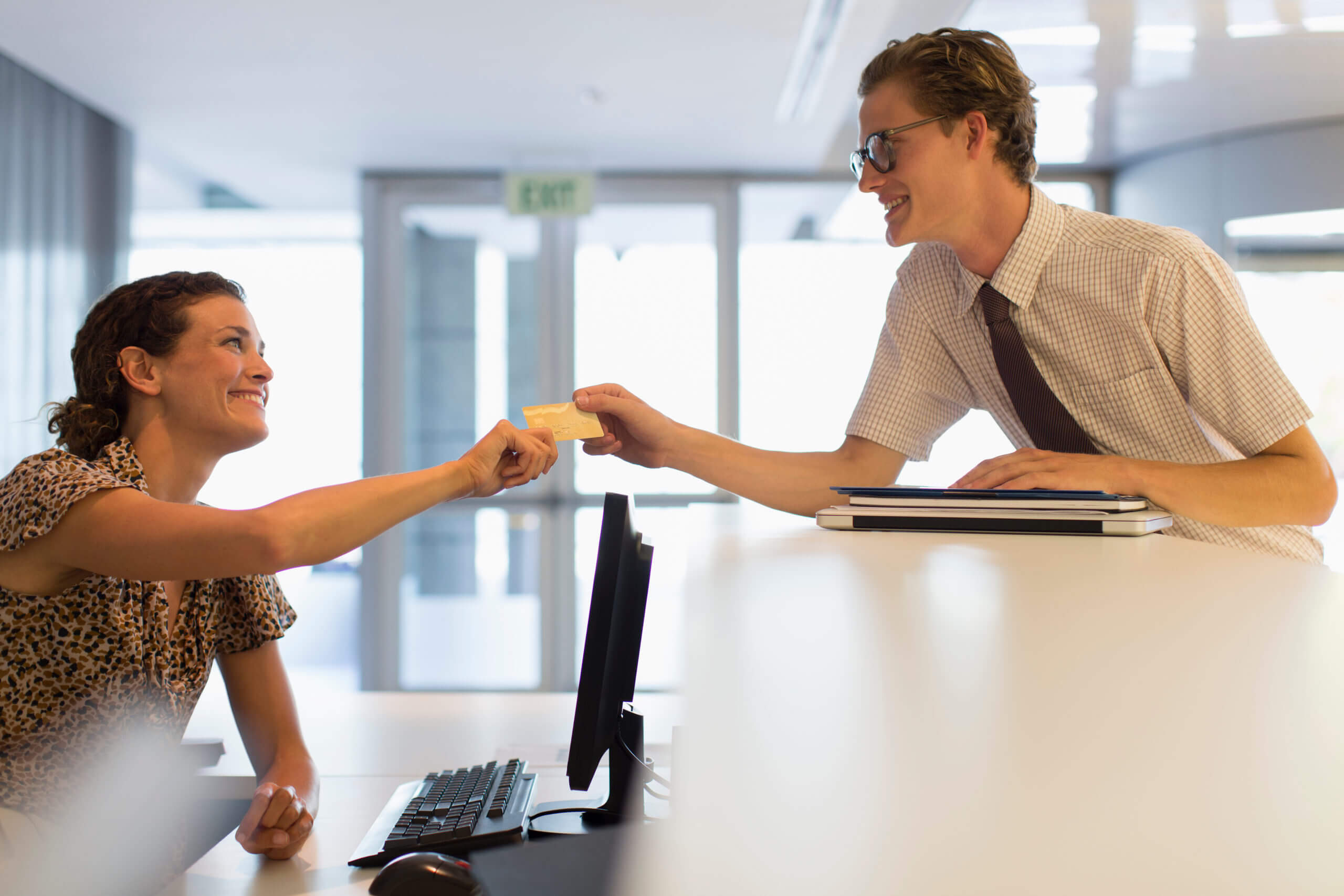 Hotel receptionist taking credit card from businessman