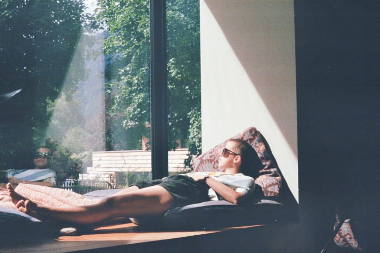 man lying on cushion by window